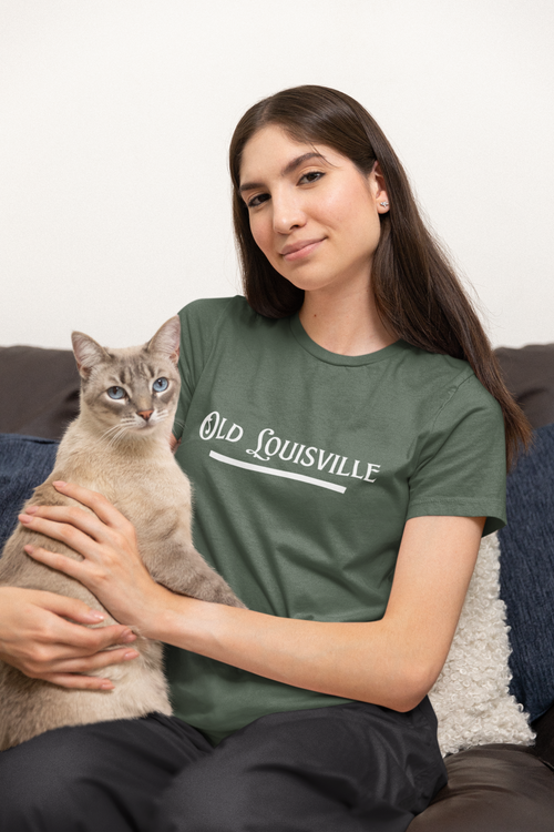 Person wearing a 'Old Louisville' t-shirt holding a cat on a couch.